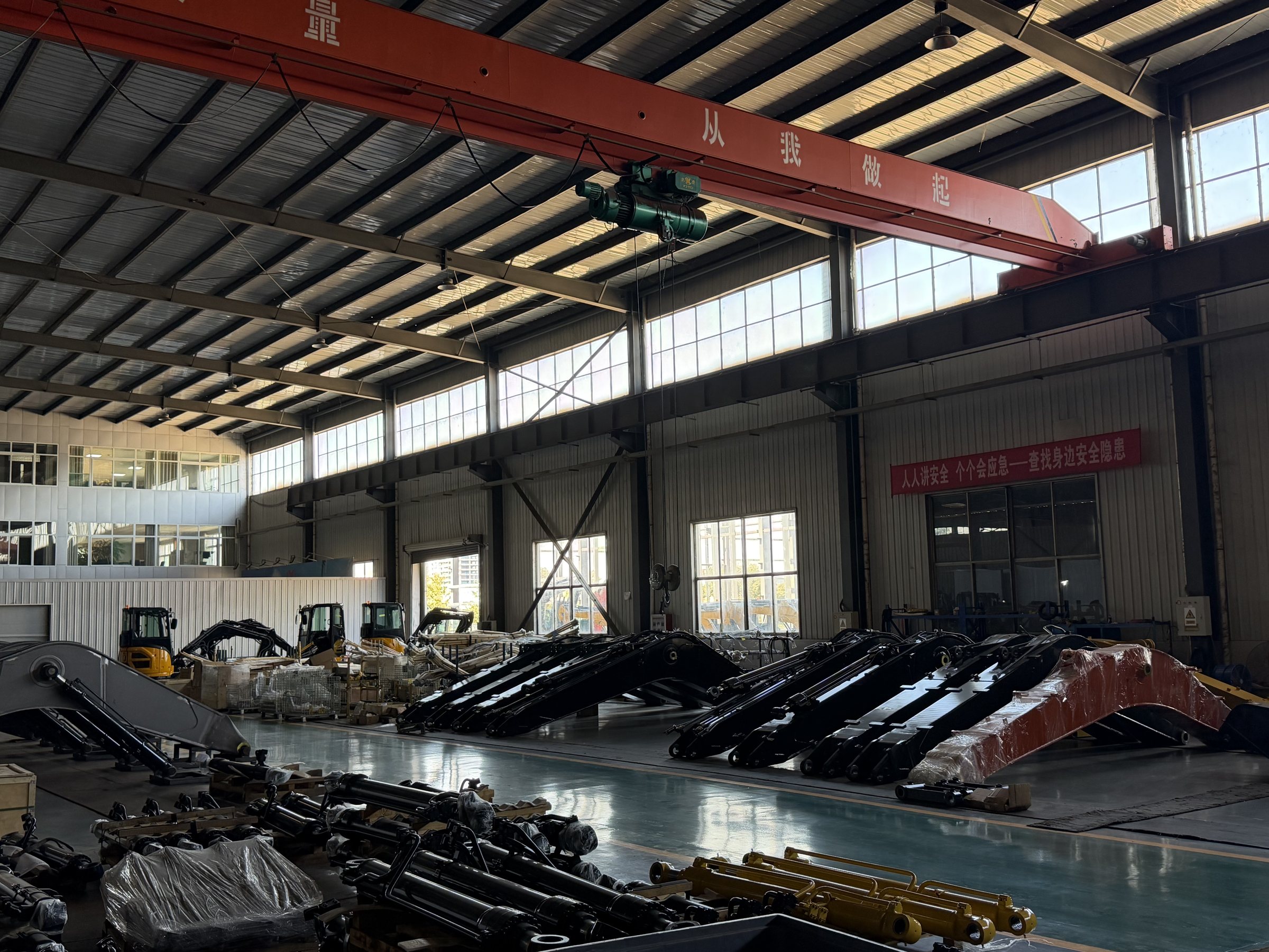 Excavator booms and hydraulic components arranged inside the TOUGH factory workshop
