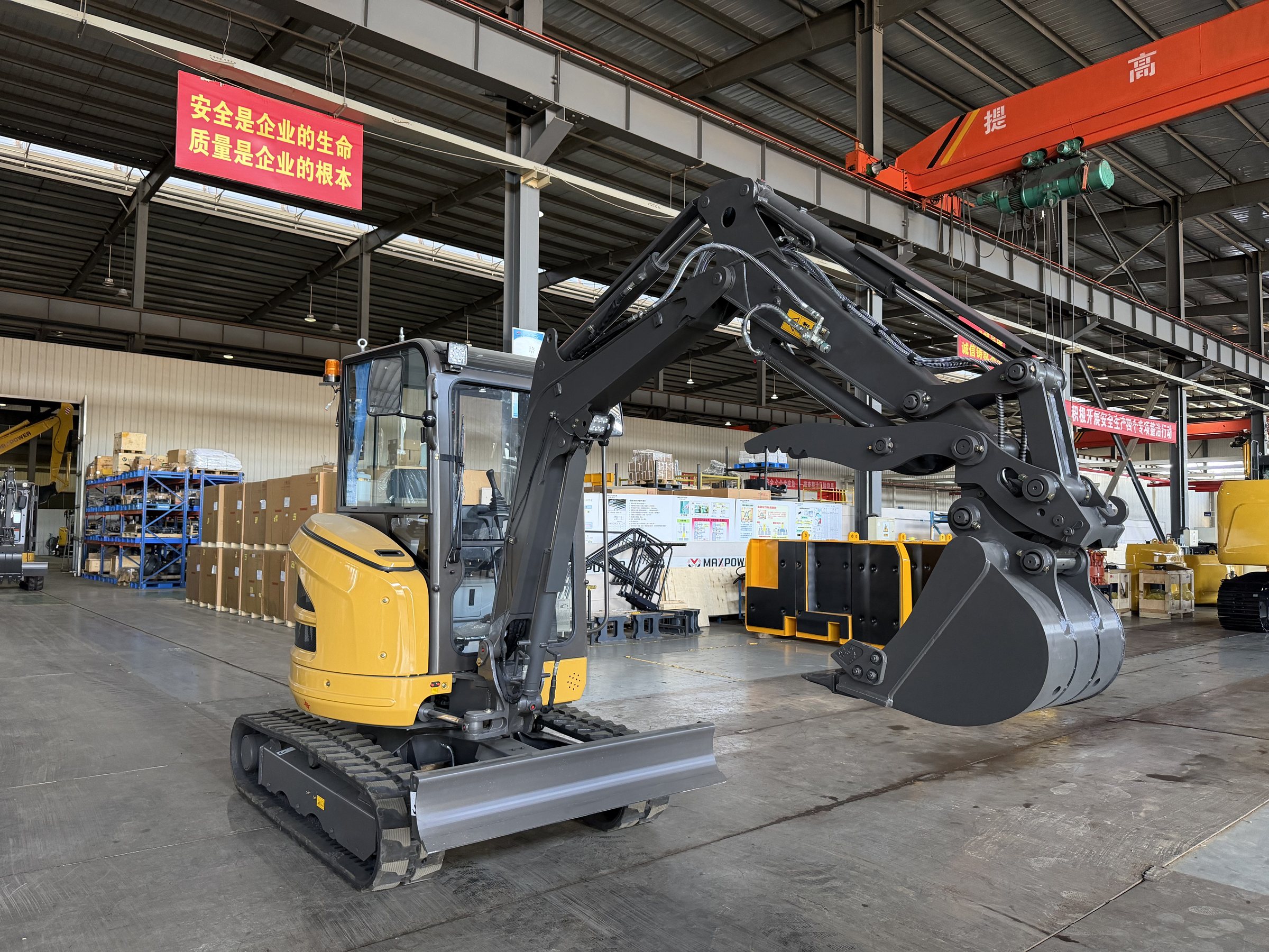 Compact excavator inside the TOUGH factory workshop with overhead lifting equipment