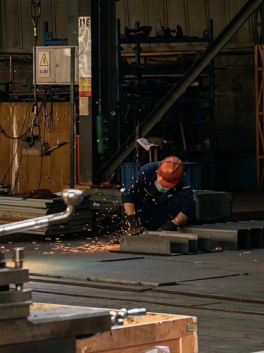 Worker welding steel components inside the TOUGHNEER factory