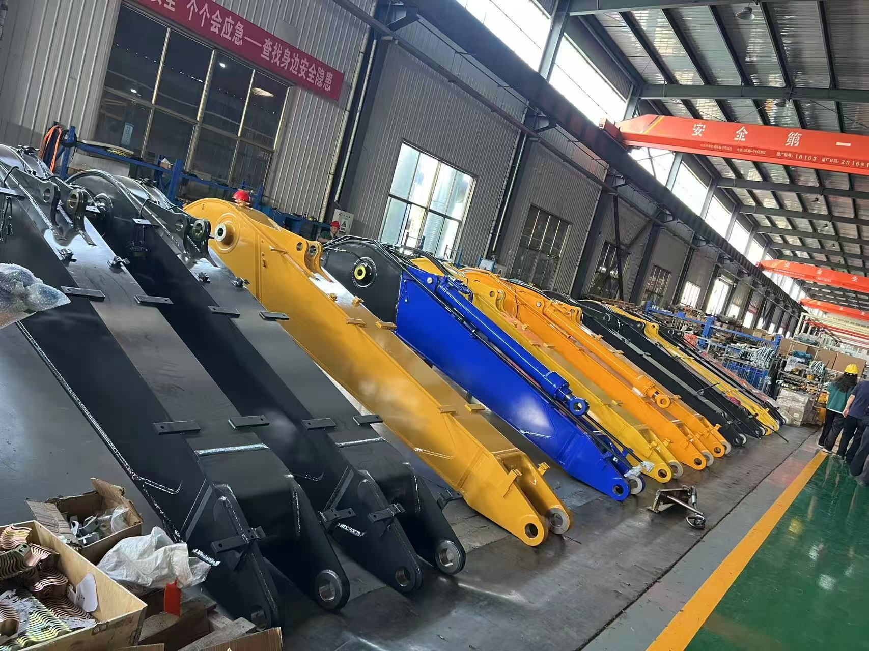 Excavator booms and attachments staged on the factory floor